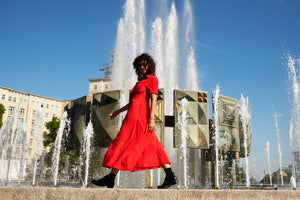 Model walking in red dress next to a fountain in Berlin.