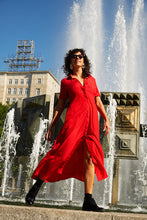 Red dress next to a fountain in Berlin, blowing in the wind.